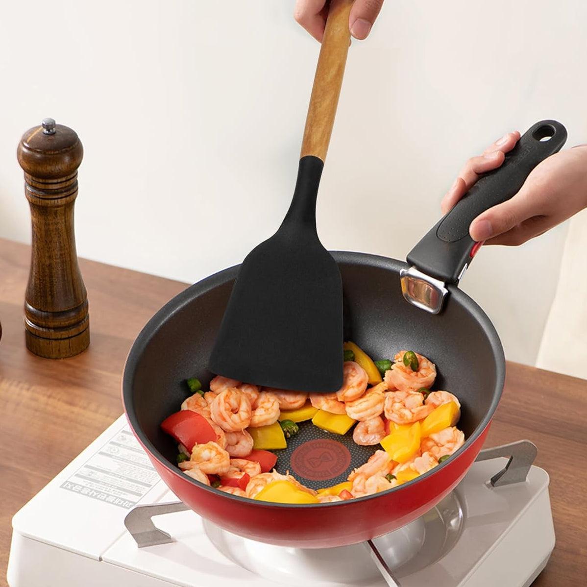 Poêle antiadhésive rouge avec crevettes et légumes, spatule en silicone, cuisson sur plaque portable