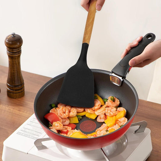 Poêle antiadhésive rouge avec crevettes et légumes, spatule en silicone, cuisson sur plaque portable